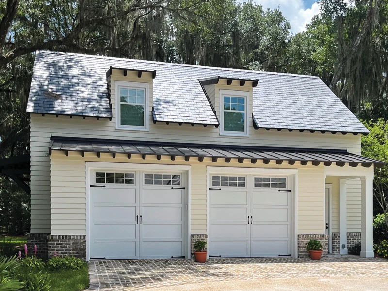Modern residential garage with white doors, decorative windows, and a stylish roof, showcasing Overhead Door Company of Fresno’s garage door solutions for home enhancement.