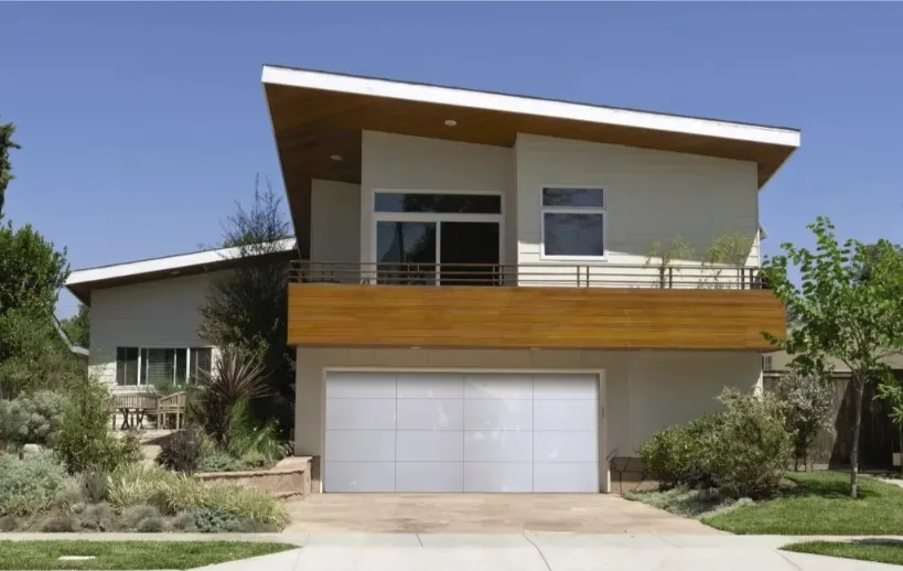 Modern residential home with a prominent garage door, showcasing sleek design and landscaping, representing garage door installation and repair services.