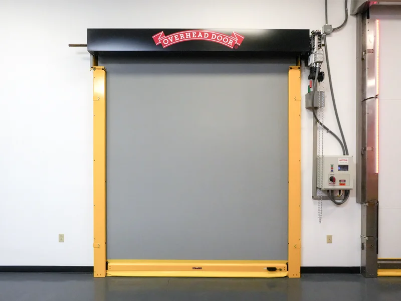 Overhead Door branded high-speed commercial door with yellow frame and gray curtain, showcasing advanced door solutions for businesses.