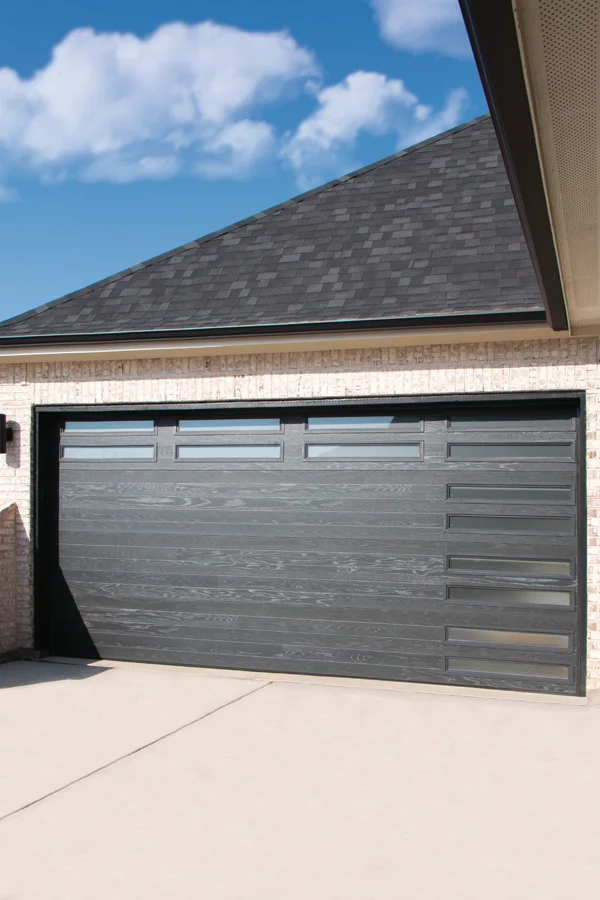 Modern residential garage door in dark wood finish with horizontal panels and windows, enhancing home style and security, featured by Overhead Door Company of Fresno™.