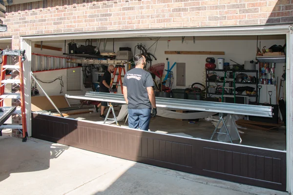 Garage door technician replacing rollers with smooth-gliding nylon options for improved performance and reduced noise in residential garage.