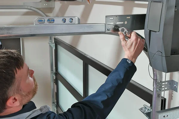 Technician adjusting garage door track and opener for proper alignment and functionality.