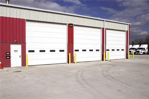Commercial garage doors with white panels and windows, designed for high-traffic areas, showcased in a professional setting.
