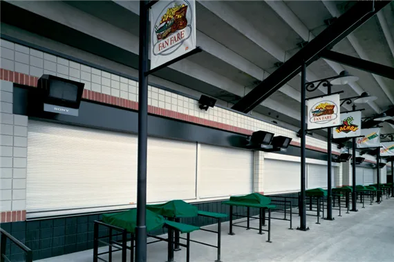Rolling counter doors installed in a commercial setting, featuring closed metal shutters and signage for food service areas, illustrating security and accessibility for retail environments.