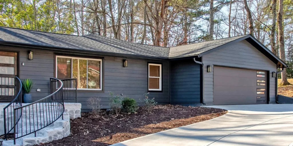 Modern home exterior featuring a dark bronze garage door with double narrow windows, complemented by a stylish entrance and landscaped surroundings, representing Overhead Door Company's residential garage door offerings.