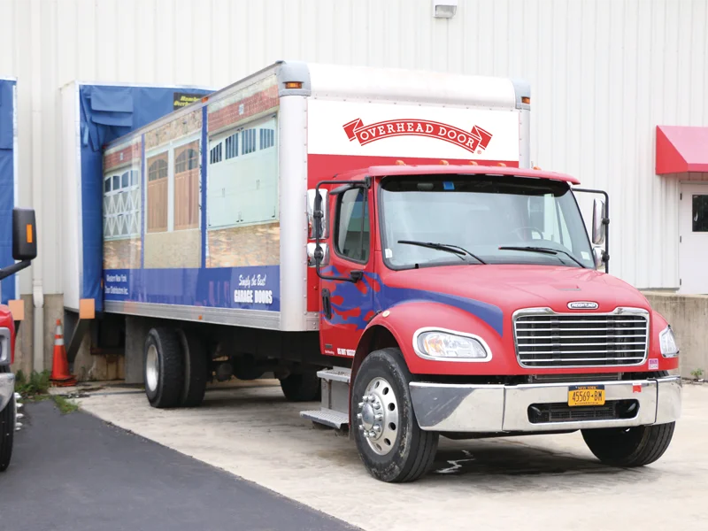 Truck with Overhead Door branding parked at a loading area, showcasing durable truck trailer doors designed for commercial fleets.